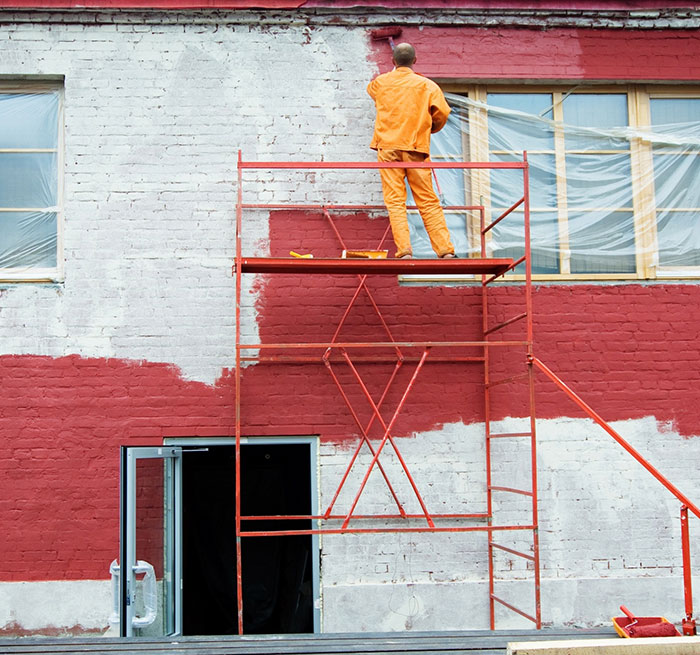exterior_img1 Commercial property exterior being painted red by a professional painter on scaffolding